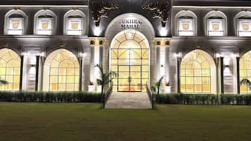 Un edificio imponente con una amplia entrada en arco, columnas y un cartel que dice "PUKHRA MAHAL".