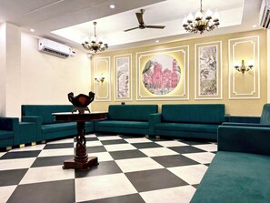 A lobby with teal sofas, a checkered floor, and wall-mounted artwork. - Rambagh Resorts By Stotrak, Gwalior (Gwalior)