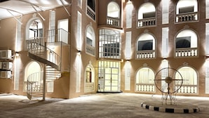 A spacious interior with a central staircase, multiple arched windows, and a decorative metal sculpture.