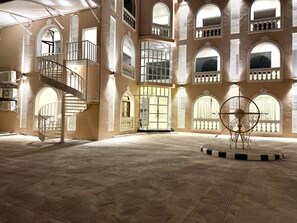A spacious interior with a central staircase, multiple arched windows, and a decorative metal sculpture. - Rambagh Resorts By Stotrak, Gwalior (Gwalior)