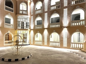 A spacious courtyard with multiple arched windows and balconies, a reception area, and a decorative metal sculpture. - Rambagh Resorts By Stotrak, Gwalior (Gwalior)