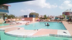 A swimming pool with people in it, surrounded by lounge chairs and umbrellas. - Express Inn Coronado & Camping (Nueva Gorgona)