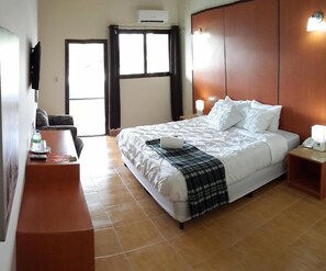 Ein Hotelzimmer mit einem Bett, Nachttischen, einem Fernseher und einem Fenster mit Vorhängen.