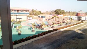 Un área de piscina con sillones de descanso, sombrillas y plantas en macetas.
