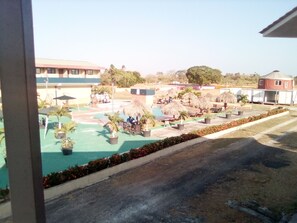 A pool area with lounge chairs, umbrellas, and potted plants. - Express Inn Coronado & Camping (Nueva Gorgona)