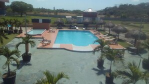 A swimming pool with lounge chairs and palm trees. - Express Inn Coronado & Camping (Nueva Gorgona)