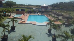 Una piscina con sillas de descanso y palmeras.
