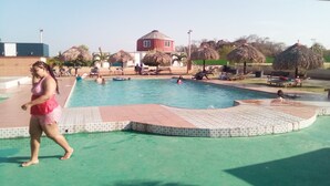A swimming pool with a tiled edge, lounge chairs, and a building in the background. - Express Inn Coronado & Camping (Nueva Gorgona)