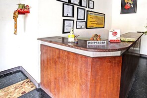 A reception desk with framed certificates on the wall, a small statue, and a 'RECEPTION' sign. - Hotel O Motel Langko (Mataram)