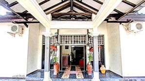 A building entrance with a tiled floor, a wooden ceiling, and a metal gate. - Hotel O Motel Langko (Mataram)
