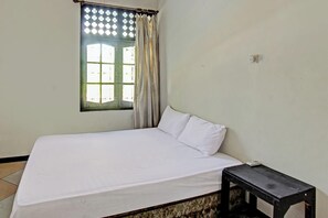 A single bed with white bedding, a small bedside table, and a window with a curtain. - Hotel O Motel Langko (Mataram)