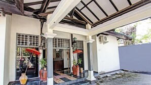 A traditional building with a covered entrance, columns, and potted plants. - Hotel O Motel Langko (Mataram)