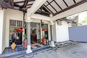 Ein traditionelles Gebäude mit überdachter Veranda, Säulen und Pflanzkübeln.