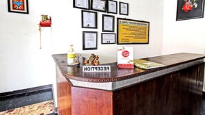 A reception desk with a sign reading 'RECEPTION,' a framed certificate, and a notice on the wall. - Hotel O Motel Langko (Mataram)