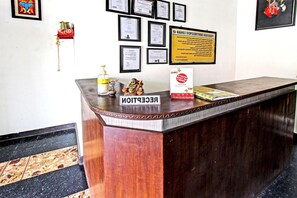 A reception desk with a sign reading 'RECEPTION,' a framed certificate, and a notice on the wall. - Hotel O Motel Langko (Mataram)