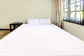 A single bed with white bedding in a room with a window featuring decorative metal bars. - Hotel O Motel Langko (Mataram)