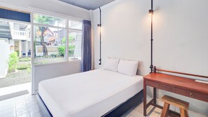 A bedroom with a bed, a wooden desk, a bench, and a window with curtains. - Collection O At Jalan Padma Legian Beach (Legian)