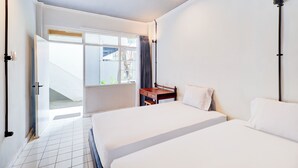 A hotel room with two beds, a desk, and a window with curtains. - Collection O At Jalan Padma Legian Beach (Legian)