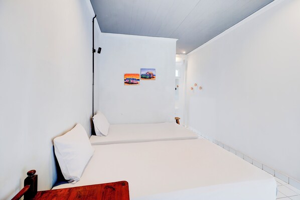 Una habitación minimalista con una cama, un banco de madera y una estantería de pared.