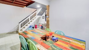 A dining area with a colorful table, chairs, and a staircase. - Collection O At Jalan Padma Legian Beach (Legian)