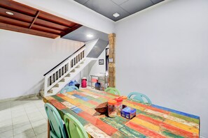 Zona de menjador amb taula i cadires de colors i una escala.