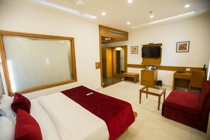 A hotel room with a bed, a desk, a chair, a television, and a mirror. - Hotel Coral Star (Chandigarh)