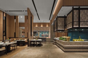 Un interior de restaurante moderno con techos altos, paneles de madera y una zona de bar central.
