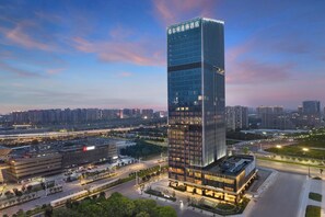A modern high-rise hotel with a glass facade, surrounded by urban infrastructure and greenery. - Doubletree by Hilton Zhengzhou East (Zhengzhou)