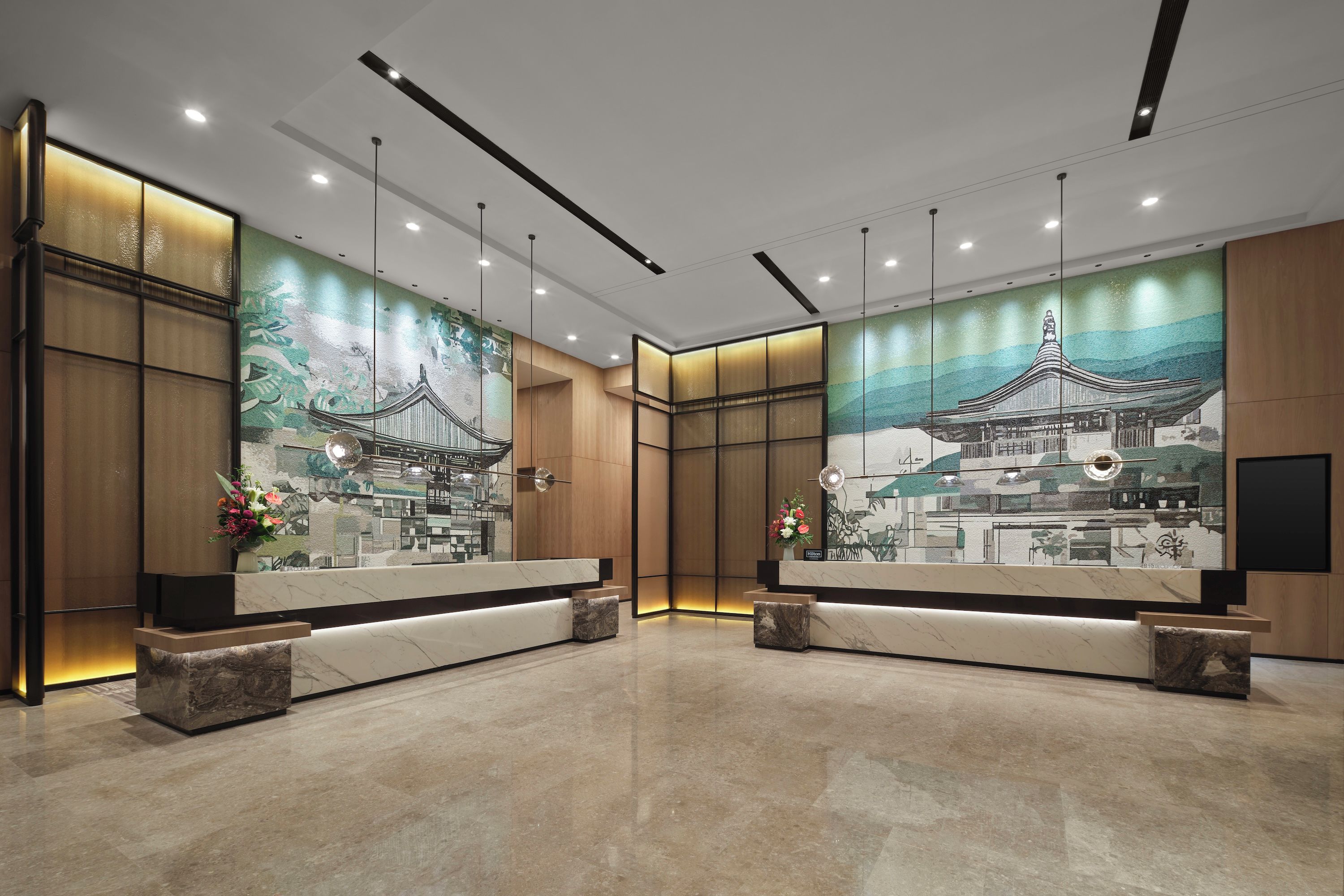 A reception area with a large mural of traditional architecture, a marble reception desk, and a modern lighting design.