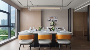Un comedor moderno con una mesa grande dispuesta para cuatro personas, rodeada de sillas con asientos acolchados y patas de metal.