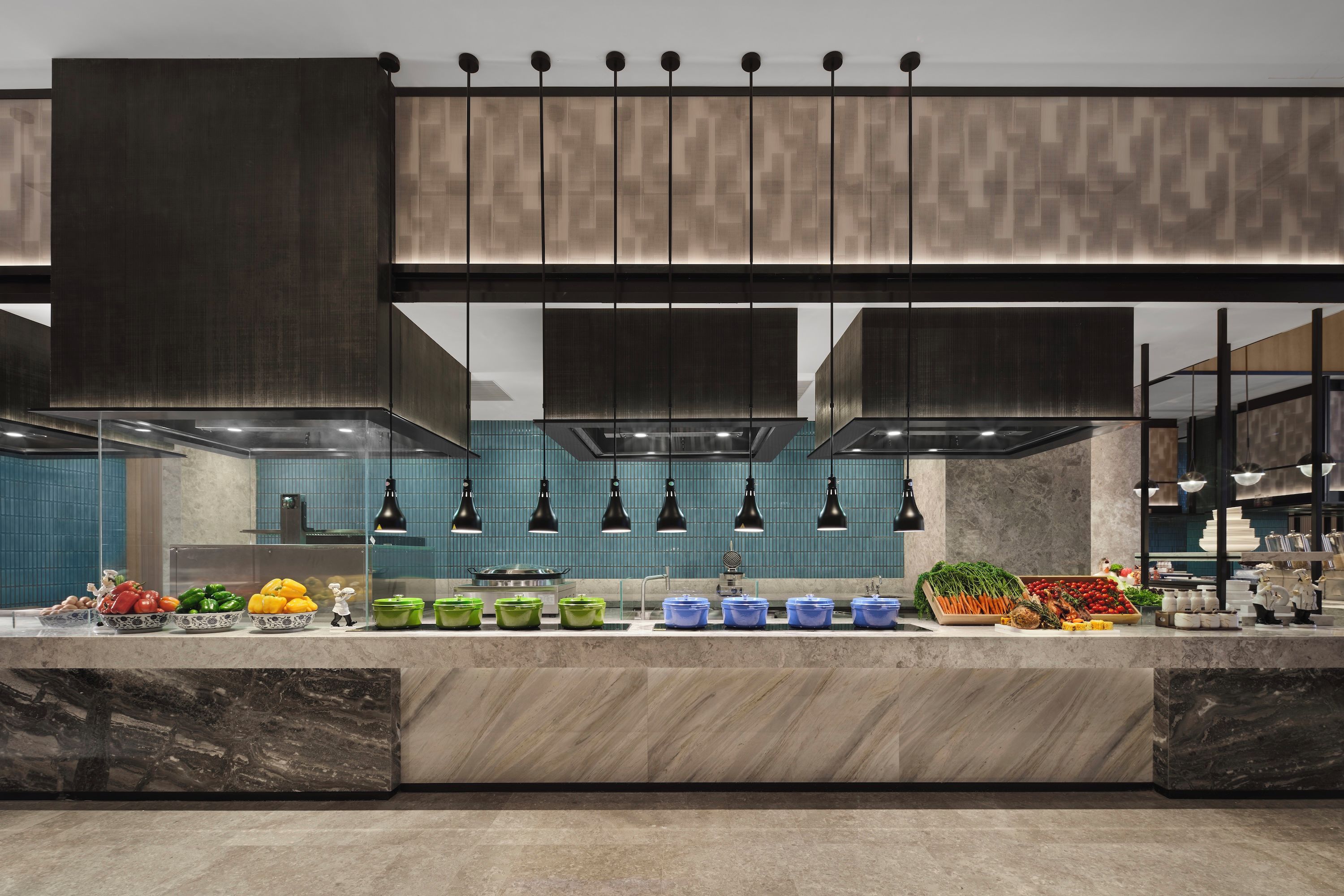 A modern kitchen with a marble countertop, green and blue storage containers, and a variety of fresh produce.