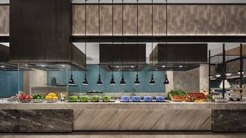 A modern kitchen with a marble countertop, green and blue storage containers, and a variety of fresh produce.