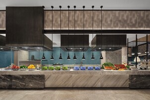 Una cocina moderna con encimera de mármol, contenedores de almacenamiento verde y azul, y gran variedad de frutas y verduras frescas.