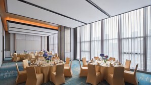 Un salón de conferencias con mesas redondas, sillas color beige y alfombra estampada azul.