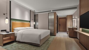 Una habitación de hotel moderna con una cama grande, una mesita de noche, un televisor de pantalla plana y un vestidor.