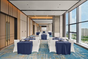 Une salle de conférence avec des tables disposées pour une réunion, de grandes fenêtres offrant une vue sur la ville et un aménagement intérieur moderne.