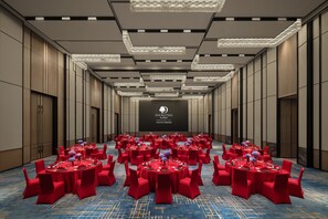 Une salle de conférence avec plusieurs tables disposées pour un événement officiel, et un grand écran installé à l’avant.