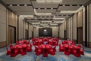 A conference room with multiple tables set for a formal event, featuring a large screen at the front.