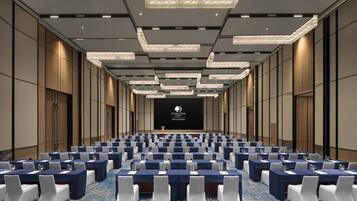 A conference room with rows of tables, chairs, and a podium.