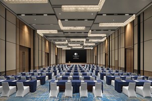 Un salón de conferencias con filas de mesas, sillas y un atril.