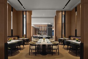 A modern dining area with high ceilings, wooden paneling, and a central bar. Tables are set with chairs, and the space is well-lit. - Doubletree by Hilton Zhengzhou East (Zhengzhou)