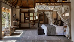 A bedroom with a canopy bed, a desk, a chair, a wardrobe, and a large window. - Toro River Lodge (Kareeberg)