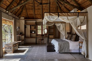 Une chambre à coucher avec un lit à baldaquin, un bureau, une chaise, une armoire et une grande fenêtre.