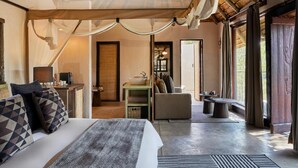 A bedroom with a bed, bedside table, and a view of a bathroom. - Toro River Lodge (Kareeberg)