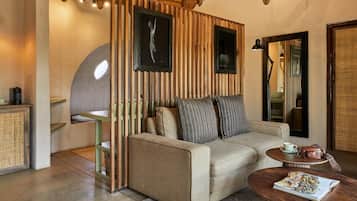 Une pièce chaleureuse avec un canapé, une petite table, un meuble et un mur recouvert de lambris en bois verticaux.