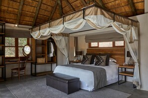 Une chambre à coucher avec un lit à baldaquin, un bureau, une chaise et un miroir.