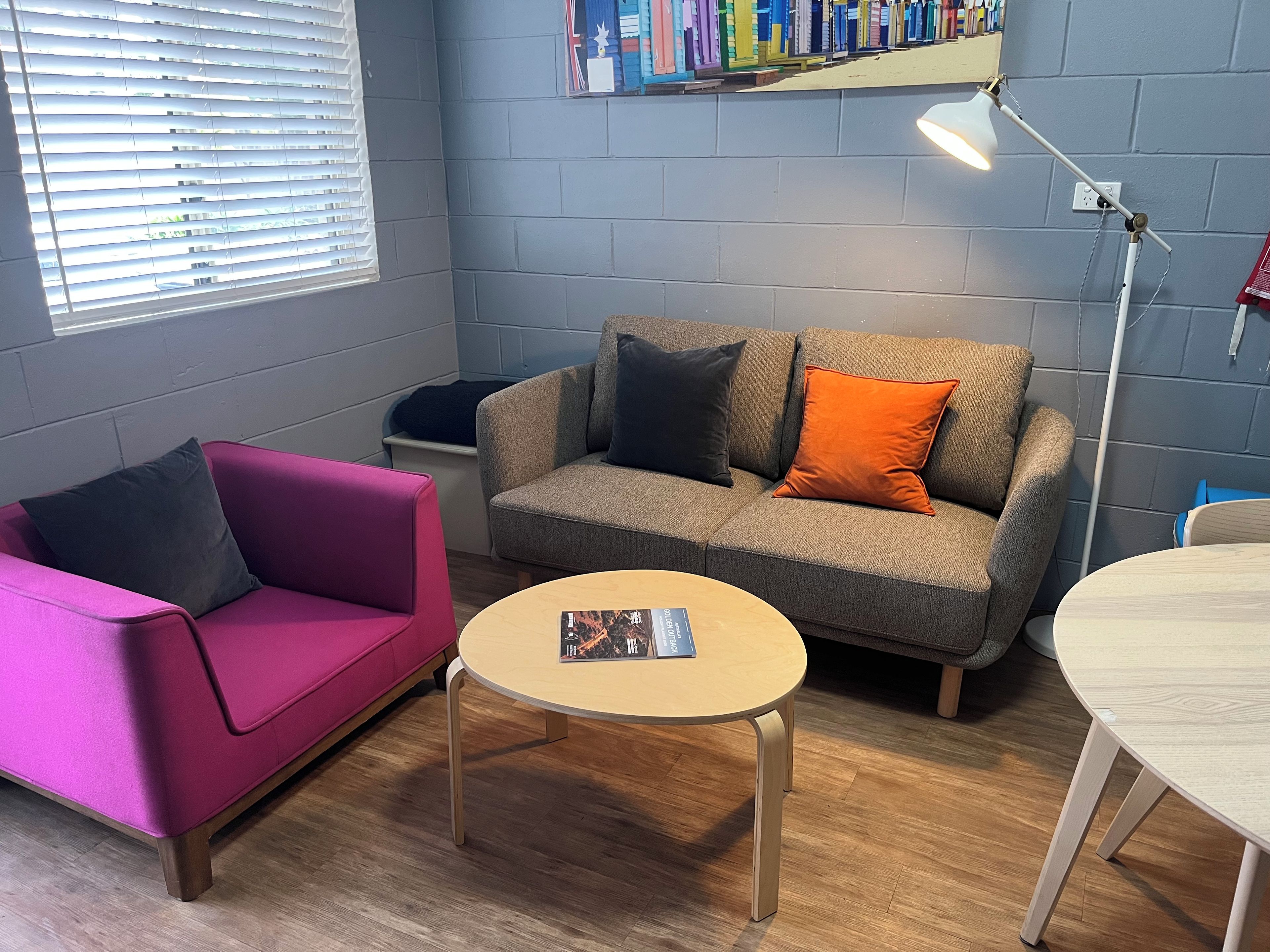 A room with a grey sofa, a pink armchair, a small round table, and a floor lamp.