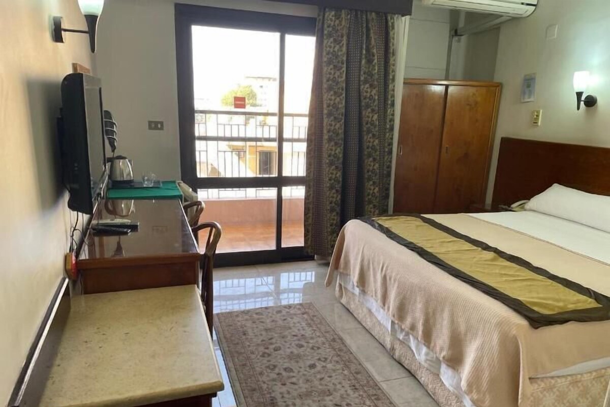 Habitació d'hotel amb llit, escriptori amb cadira, televisió i armari.