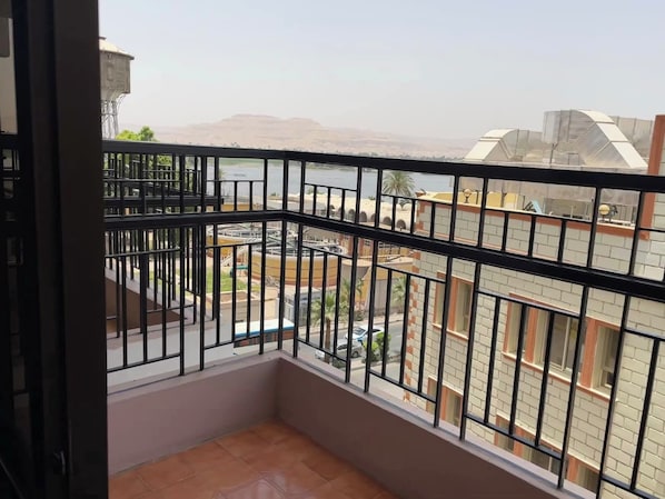 A balcony with a metal railing overlooking a residential area with buildings and a distant hill. - Stjosephhotel (Luxor)