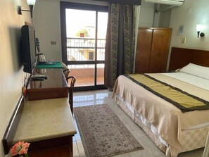 Una habitación de hotel con cama, escritorio, silla, televisor y armario.